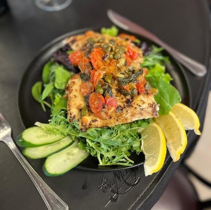 Pescado grillé sobre hojas verdes, con limón